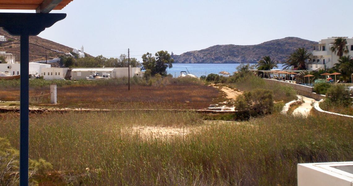 Scenic view of the Aegean Sea and the hilltop Chora of Ios with its iconic white church, seen from the hotel grounds.