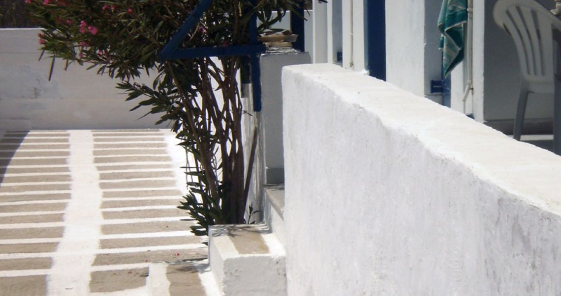Close-up of white-washed outdoor steps and a traditional stone walkway typical of Ios island architecture.