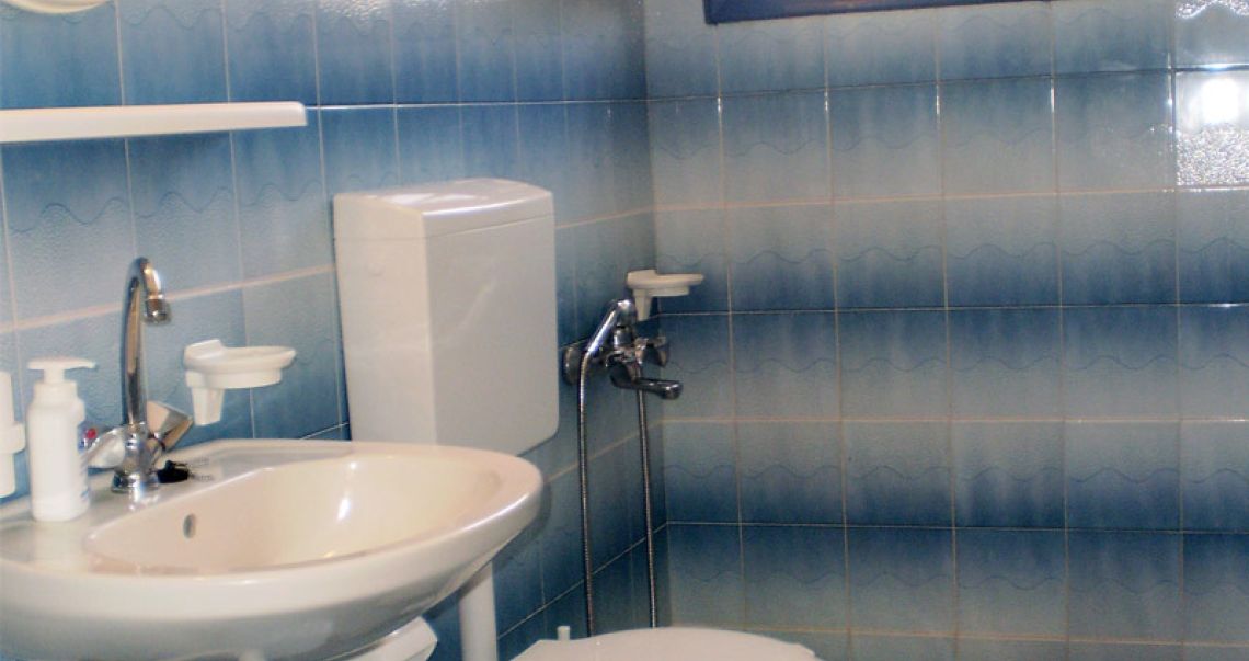 Clean hotel bathroom with a blue and white wave-patterned tile design, complete with a sink, toilet, and shower area.