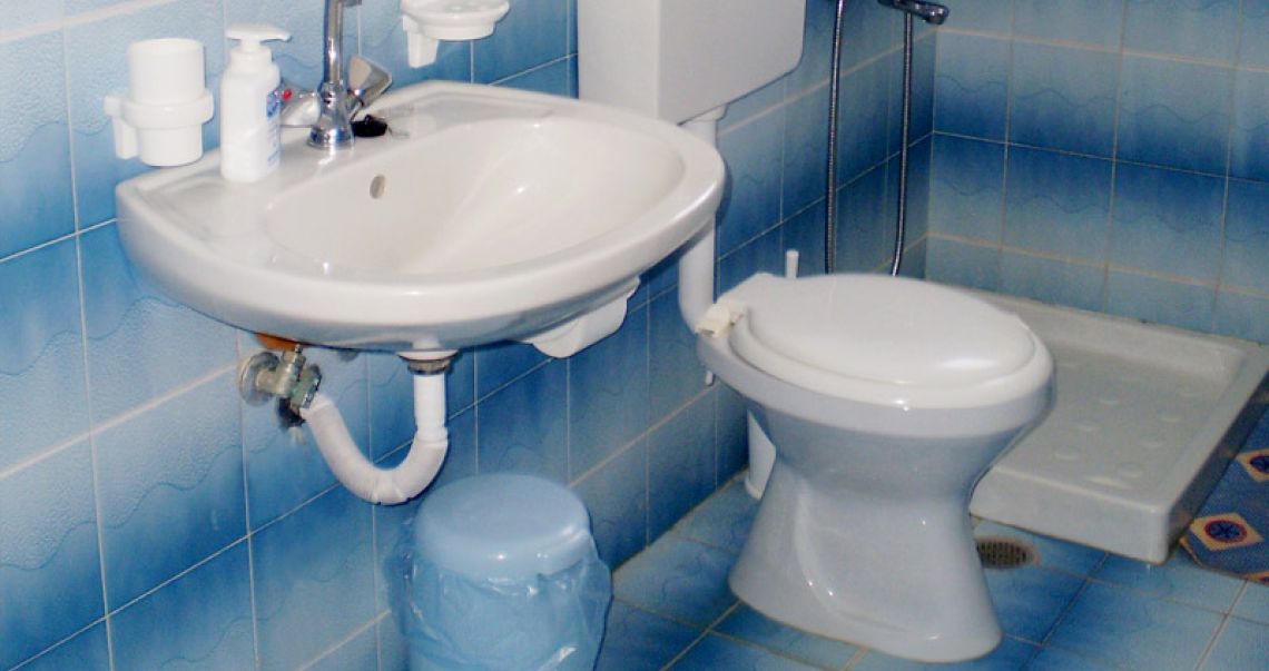 Bright hotel bathroom featuring blue-toned tiling, a white porcelain sink, and a clean, functional layout.