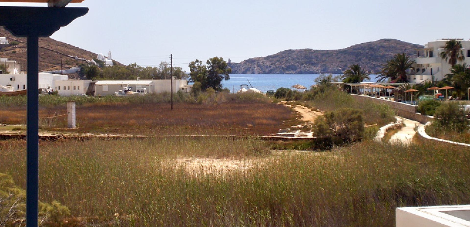 Scenic view of the Aegean Sea and the hilltop Chora of Ios with its iconic white church, seen from the hotel grounds.