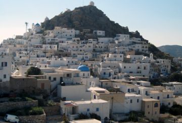 Panoramic view of the traditional white-washed houses and blue-domed churches of Chora, Ios, nestled on the hillside.